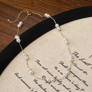Gros plan d'un collier de perles doré délicat sur un support en tissu littéraire