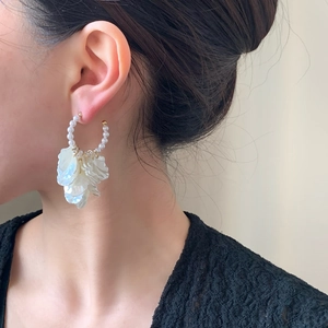 Elegant gold pearl flower hoop earrings worn by a model in a close-up profile shot