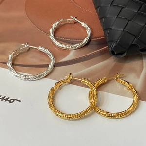Luxurious twisted hoop earrings in gold and silver finish with textured metal surface