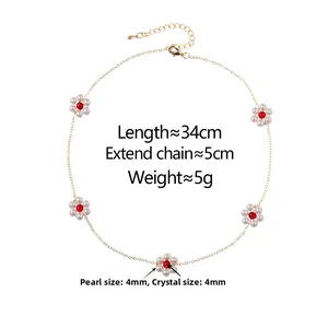 Close-up of gold chain with five pearl flower charms and red crystal centers