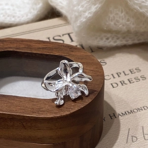 Detailed view of silver orchid ring with zircon stone on a wooden jewelry box