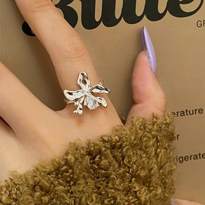 Close-up of orchid-shaped silver ring with zircon stone on a woman's finger