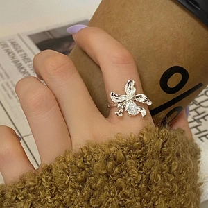 Macro detail of orchid-inspired gold ring with sparkling marquise zircon on finger