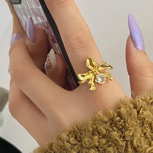 Golden orchid flower ring with zircon stone shown on a model hand with luxury nail art