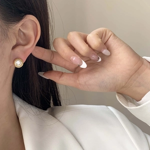Boucles d'oreilles puces rondes en or avec halo de diamants portées par un mannequin en blanc