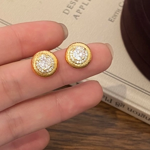 Gros plan sur un clou d'oreille doré vintage avec pierre centrale et texture