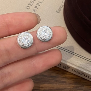 Gros plan de boucles d'oreilles vintage argentées avec zircon sur les doigts
