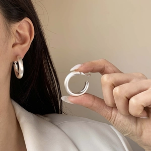 Gros plan détaillé de boucles d'oreilles créoles épaisses en argent mat brossé