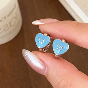 Light blue heart enamel hoop earrings with silver bow design on a wood background
