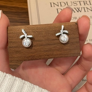 Détails des boucles d'oreilles nœud en argent avec zircons pavés et perles blanches