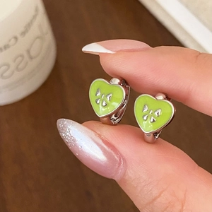 Elegant silver heart earrings with green enamel and bow detail shown in hand
