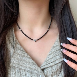 Close-up of beaded necklace with black beads and a polished silver heart pendant