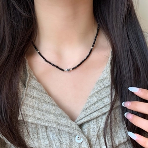 Detailed view of beaded black necklace featuring a silver heart pendant on neck