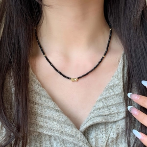 Elegant beaded necklace featuring faceted black beads and gold accents on female model