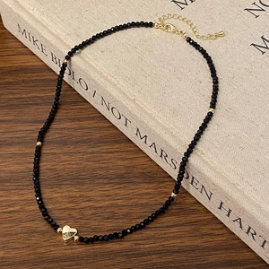 Detail of beaded necklace with gold heart pendant on vintage book and wood background