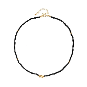 Close-up of black beaded necklace with golden curved accent and faceted texture