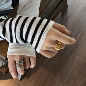 Dettaglio di anelli a spirale multistrato in oro e argento sulla mano di una modella
