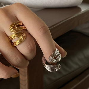 Dettaglio di anelli a spirale sovrapposti in oro e argento sulla mano della modella