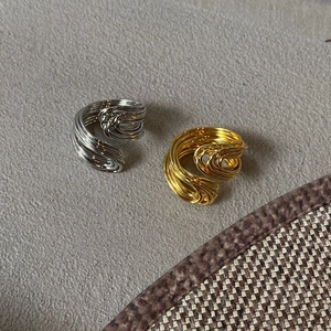 Dettaglio di anelli a più strati intrecciati in finitura oro e argento metallizzato