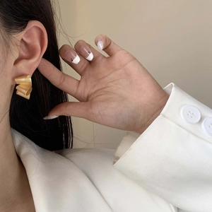 Minimalist irregular twisted matte gold earrings on model in professional white attire