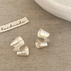 Detail showing irregular twisted matte silver stud earrings with minimalist wavy design