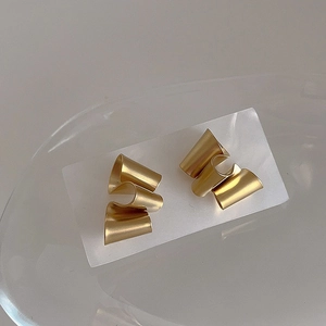 Detailed macro view of matte gold irregular twisted earrings with tiered ribbon design