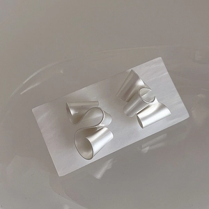 Macro detail of abstract twisted matte silver geometric earrings on a white display card