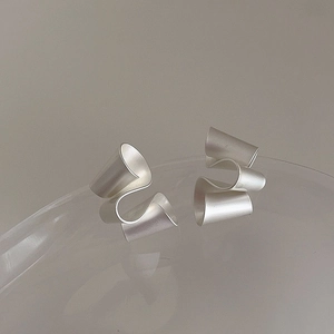 Detailed view of irregular matte silver twisted geometric earrings with ribbon texture