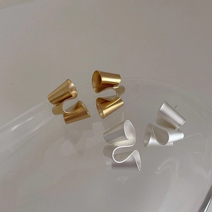 Detailed macro view of irregular twisted matte gold and silver geometric stud earrings