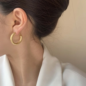 Chic gold-plated hoop earrings with a matte frosted texture worn by a model
