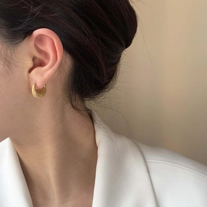 Elegant U-shape golden brushed teardrop earrings on model with minimalist business suit