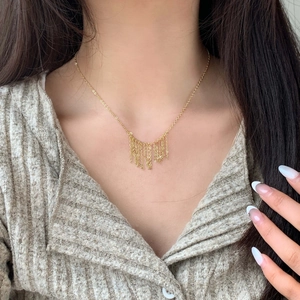 Minimalist 18K gold tassel necklace with layered delicate chains on model neck