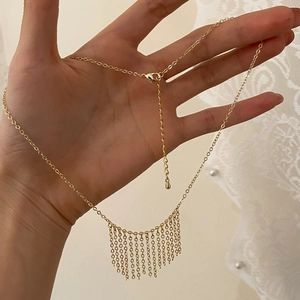 Detail of gold tassel necklace with adjustable chain and lobster clasp on lace
