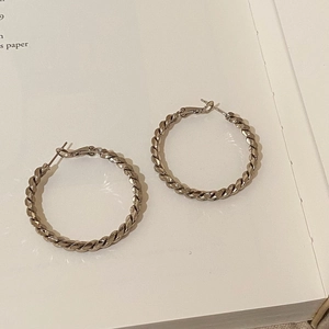 Vue détaillée de créoles torsadées en argent avec texture de métal tressé