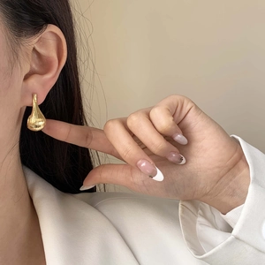 Elegant gold water drop earrings with vertical texture worn with a white blazer