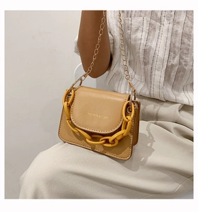Detail of mini tan crossbody bag with bold yellow chain and gold shoulder strap