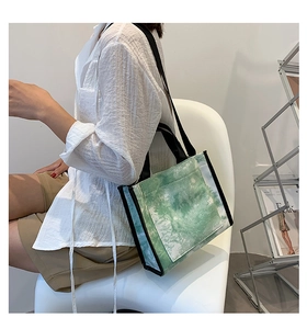 Detail of green tie-dye canvas tote bag with black strap in a modern lifestyle setting