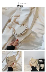 Detail view of cream-white mini shoulder bag with gold chain and plastic decorative link