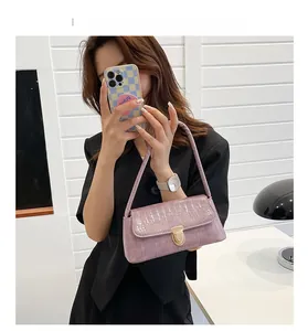 Détail du sac baguette lilas clair avec texture crocodile et fermoir doré sur modèle