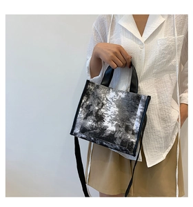 Detail of a square landscape print canvas tote bag with black leather handles and straps