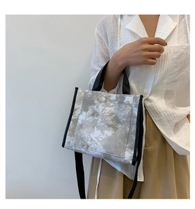 Detail of contrast canvas tote bag featuring grey marble dye pattern and black handles