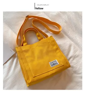 Detail of yellow canvas tote bag featuring vintage label with handle and shoulder strap