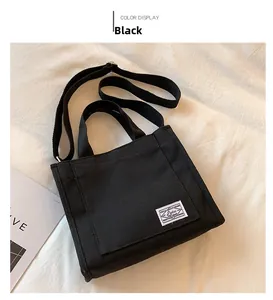Detail of black canvas tote bag with adjustable shoulder strap and woven logo label