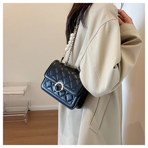 Detail of elegant black quilted crossbody bag with pearl ring buckle and chain strap