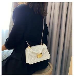 Detailed side view of white quilted crossbody bag with gold chain strap on female model