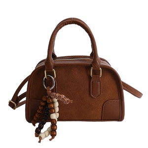 Borsa a mano retrò marrone con dettagli opachi e ciondolo in legno dallo stile minimalista