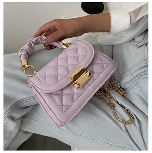 Detail of light purple quilted bag with gold hardware and ruched handle on denim