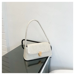 Détail de la texture croco blanc et du fermoir métallique doré sur le sac à bandoulière