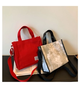 Detail showing dual-strap canvas tote bags in red and vintage prints with leather handles