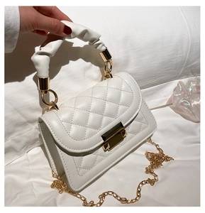 Close-up of quilted white crossbody bag with a ruched handle and gold chain strap